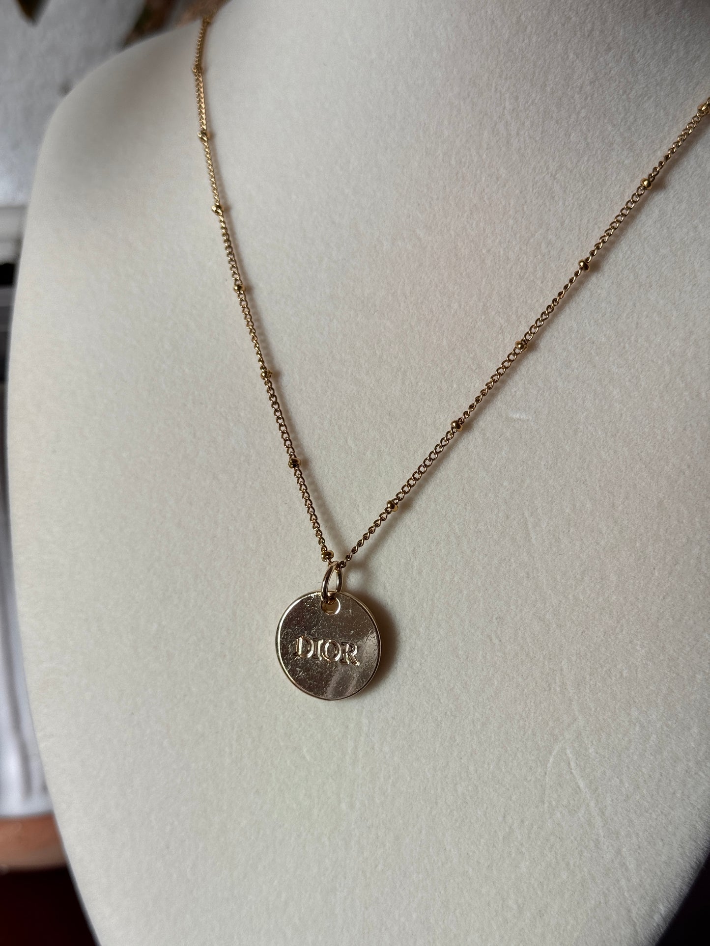 Gold necklace with a round pendant on a white surface