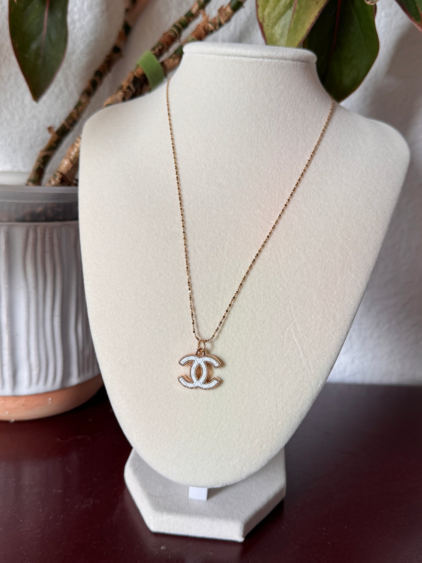 Chanel necklace on a white stand with blurred background