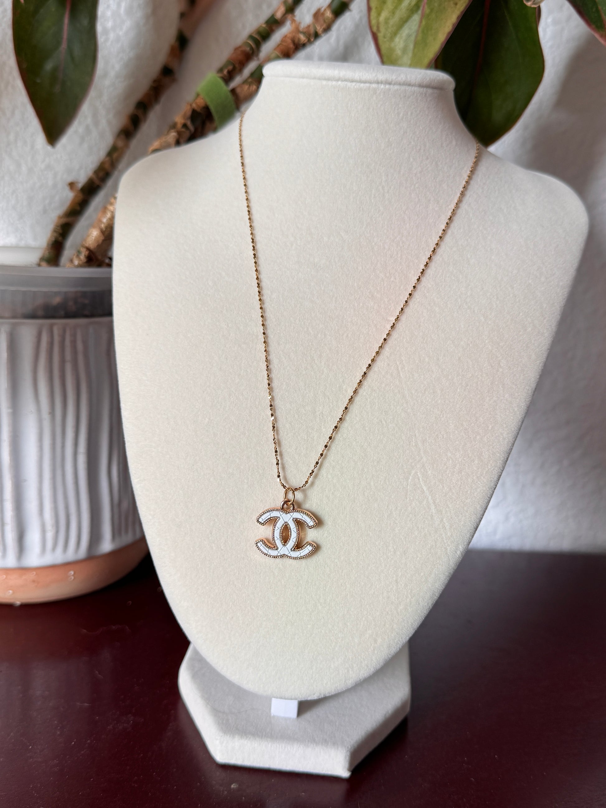 Chanel necklace on a white stand with blurred background