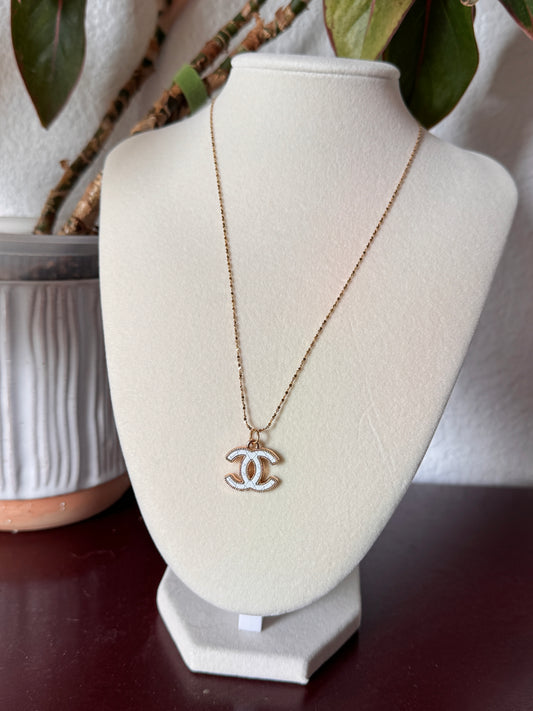 Chanel necklace on a white stand with blurred background